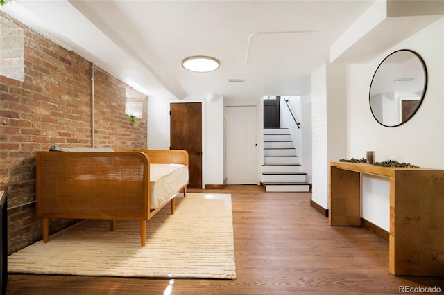 interior space with wood-type flooring and brick wall