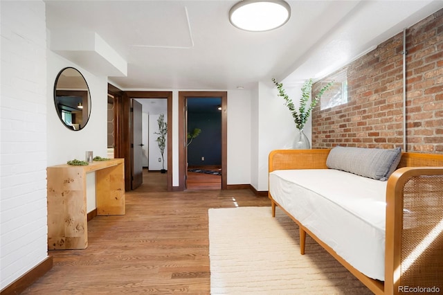 living area featuring hardwood / wood-style flooring and brick wall