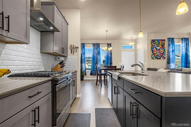 kitchen featuring decorative light fixtures, gray cabinets, wall chimney exhaust hood, and appliances with stainless steel finishes
