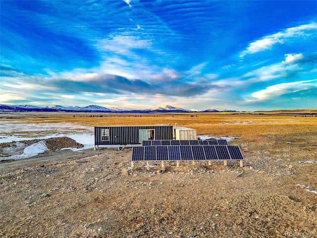 rear view of property featuring a mountain view, a rural view, and solar panels