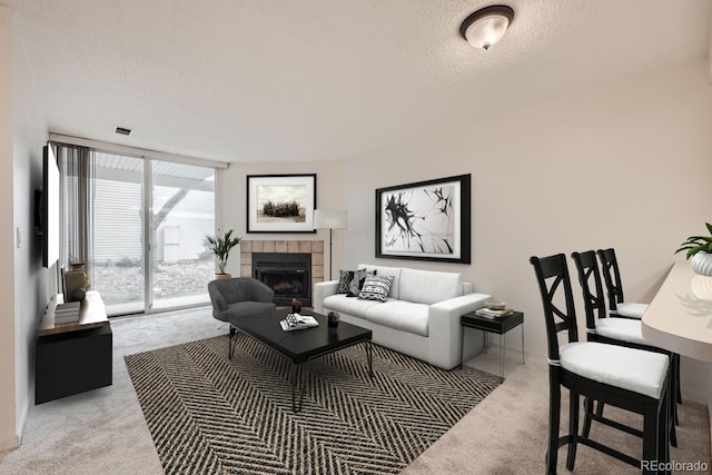 carpeted living room featuring a textured ceiling, a tile fireplace, a wall of windows, and visible vents