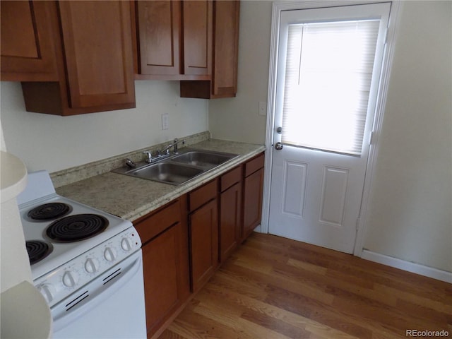 kitchen featuring white electric stove, sink, and light hardwood / wood-style flooring