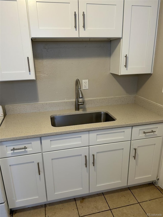 kitchen featuring light tile patterned floors, light stone countertops, sink, and white cabinets