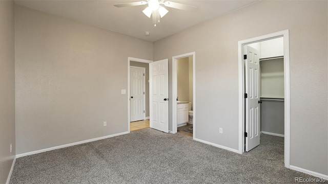 unfurnished bedroom with ceiling fan, ensuite bathroom, carpet floors, a walk in closet, and a closet