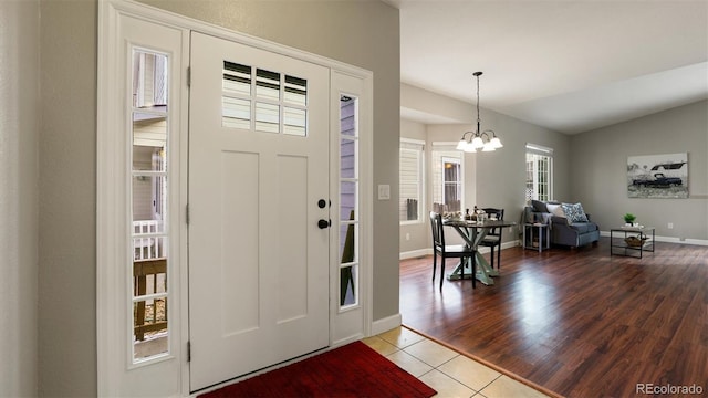 tiled foyer with vaulted ceiling and a chandelier