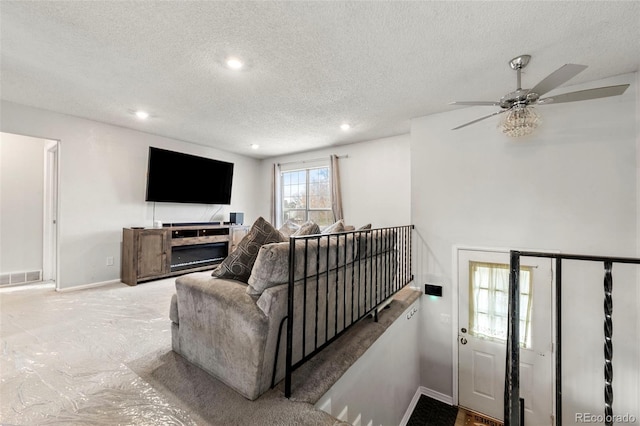 carpeted living room featuring ceiling fan and a textured ceiling