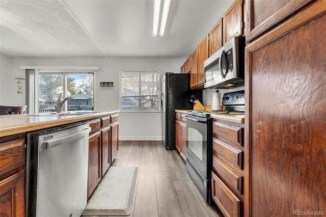 kitchen featuring sink, stainless steel appliances, a textured ceiling, and light hardwood / wood-style floors