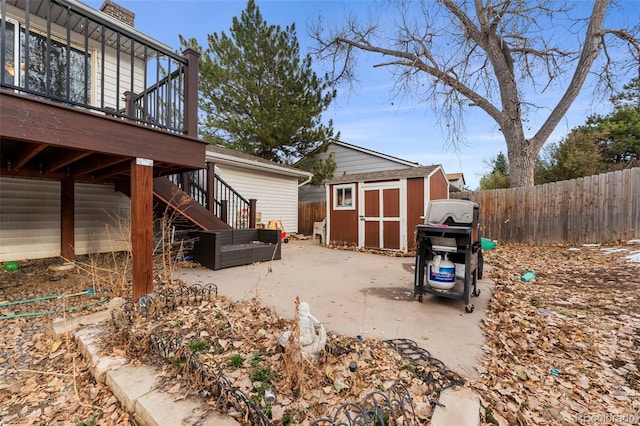 exterior space featuring a wooden deck, a patio, and a storage shed