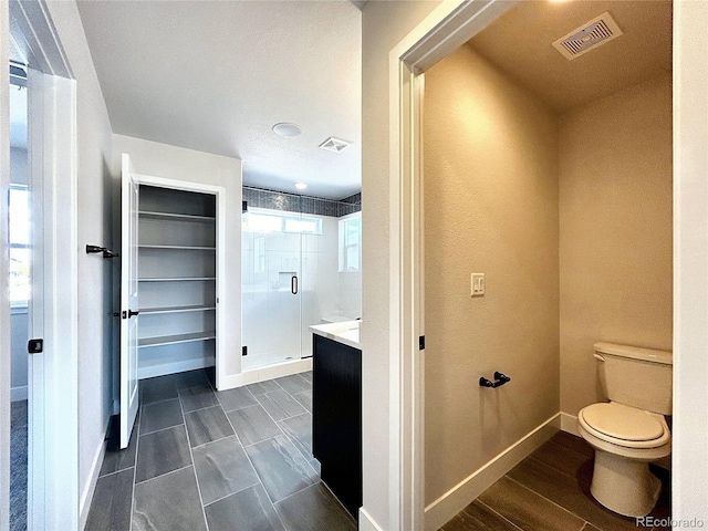 bathroom with hardwood / wood-style flooring, walk in shower, vanity, and toilet