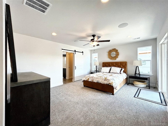 carpeted bedroom with a barn door and ceiling fan