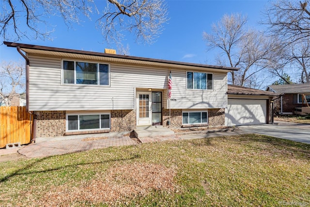 raised ranch featuring a front lawn, fence, concrete driveway, a garage, and brick siding