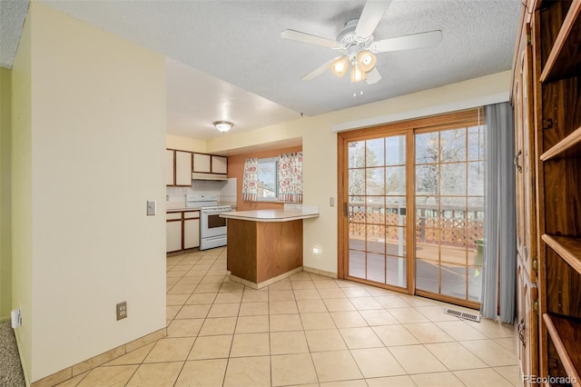 kitchen featuring visible vents, white range with electric cooktop, a peninsula, light tile patterned flooring, and under cabinet range hood