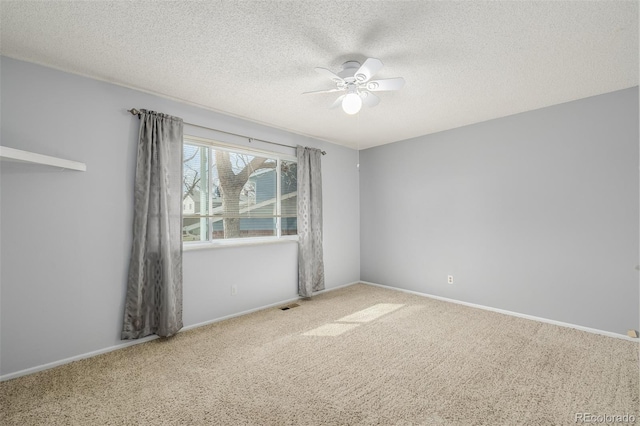 empty room featuring visible vents, a textured ceiling, a ceiling fan, and carpet