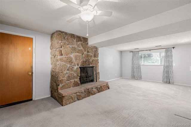 carpeted living room featuring baseboards, a stone fireplace, a textured ceiling, and a ceiling fan