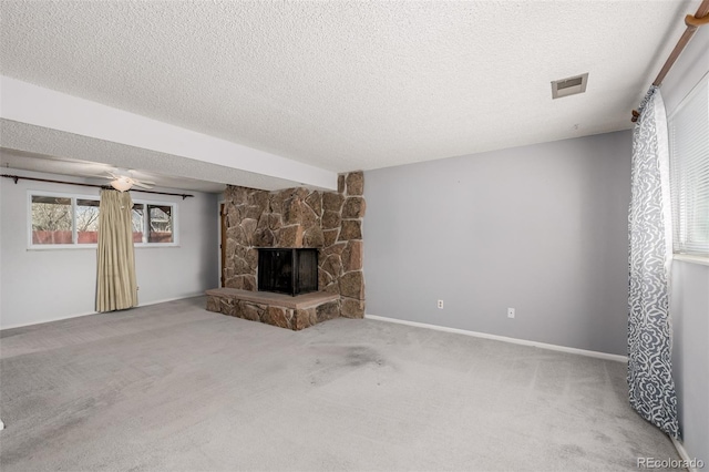 unfurnished living room featuring a fireplace, visible vents, carpet floors, and a textured ceiling