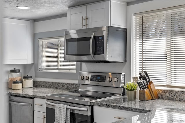 kitchen featuring a textured ceiling, stainless steel appliances, and white cabinets