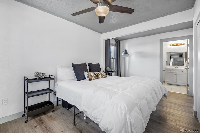 bedroom featuring wood-type flooring, sink, a textured ceiling, and ensuite bath