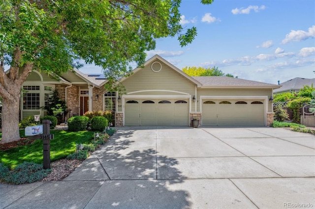 3145 Stevens Cir, Erie, CO 80516 - view of front of house featuring an attached garage, stone siding, roof mounted solar panels, and concrete driveway
