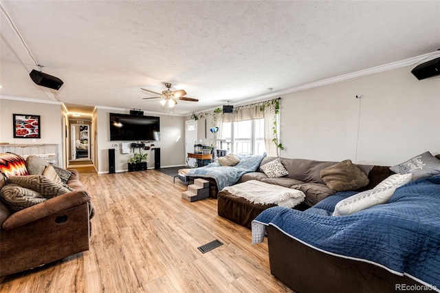 living room featuring crown molding, ceiling fan, a textured ceiling, and light wood-type flooring