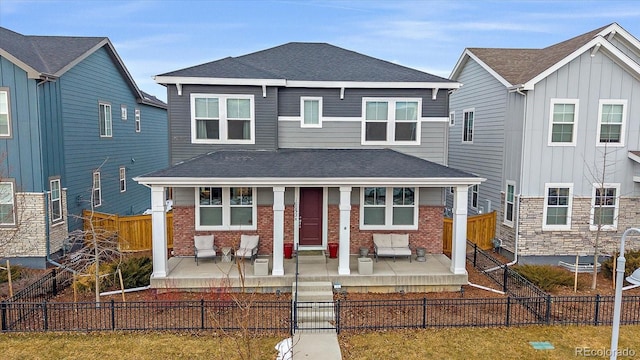 view of front of home with a porch, a shingled roof, and a fenced front yard