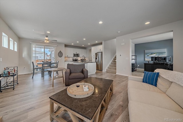 living room with sink, ceiling fan, and light wood-type flooring