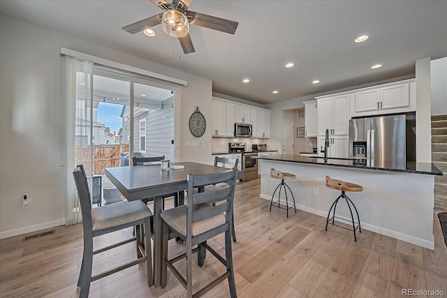 dining room with sink, light hardwood / wood-style flooring, and ceiling fan