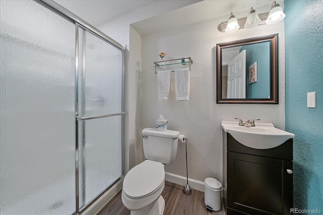 bathroom with hardwood / wood-style flooring, vanity, a shower with door, and toilet