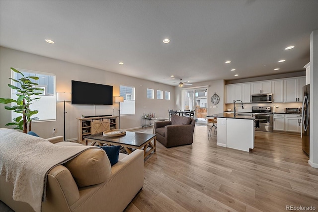 living room featuring sink, ceiling fan, and light wood-type flooring