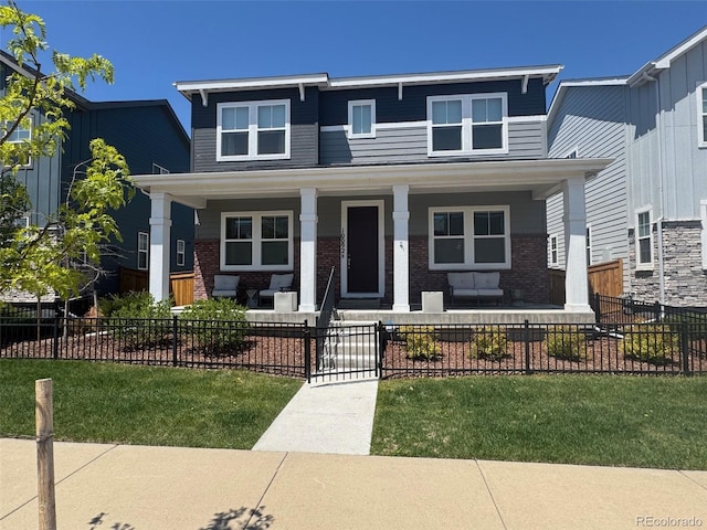 10092 Flower St, Broomfield, CO 80021 - view of front facade featuring covered porch, brick siding, and a fenced front yard