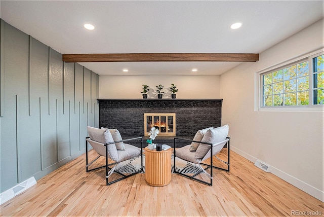 sitting room featuring beamed ceiling, light hardwood / wood-style flooring, and a fireplace