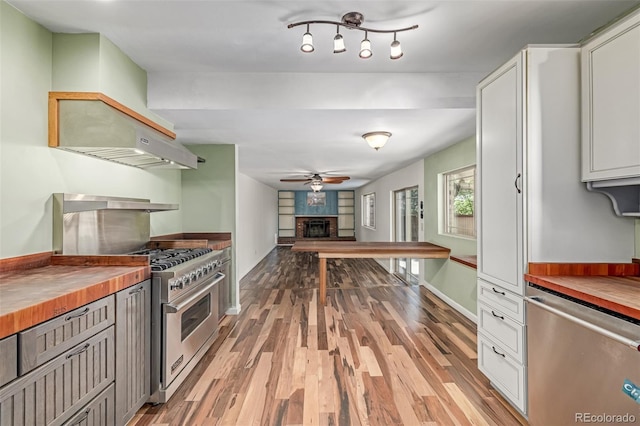 305 Titan St, Aurora, CO 80011 - kitchen featuring butcher block countertops, stainless steel appliances, ceiling fan, light wood-type flooring, and a fireplace with raised hearth