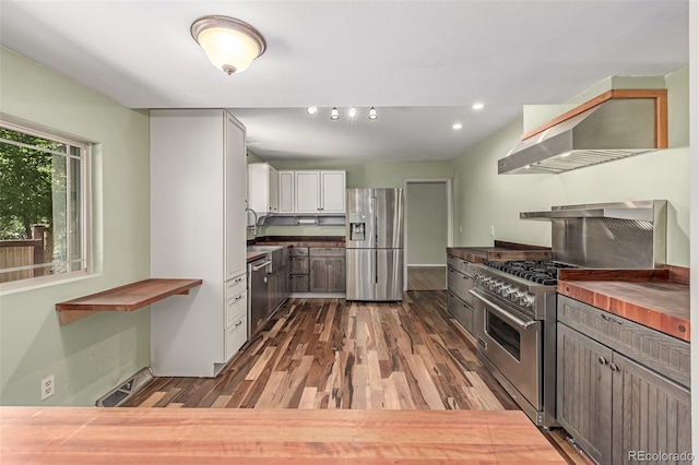 305 Titan St, Aurora, CO 80011 - kitchen with stainless steel appliances, wood counters, wood finished floors, wall chimney range hood, and white cabinets