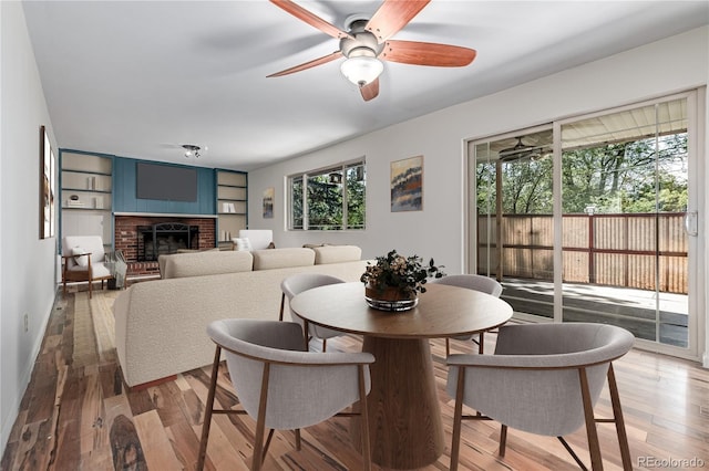 305 Titan St, Aurora, CO 80011 - dining space with healthy amount of natural light, a ceiling fan, a fireplace, and light wood-style floors