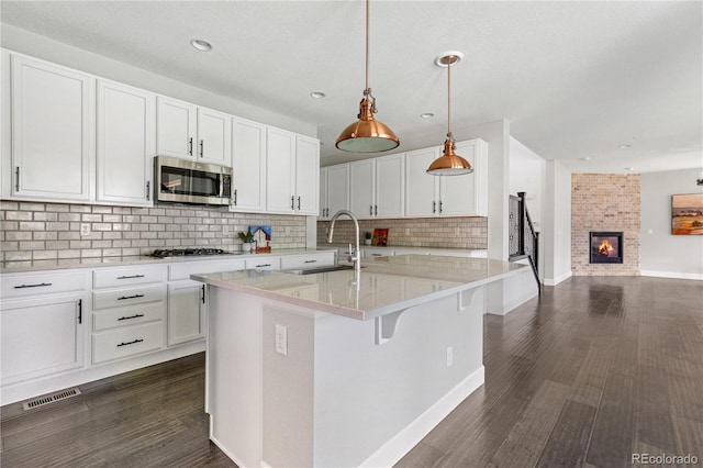 15378 W 50th Pl, Golden, CO 80403 - kitchen featuring stainless steel microwave, tasteful backsplash, gas cooktop, white cabinets, and recessed lighting