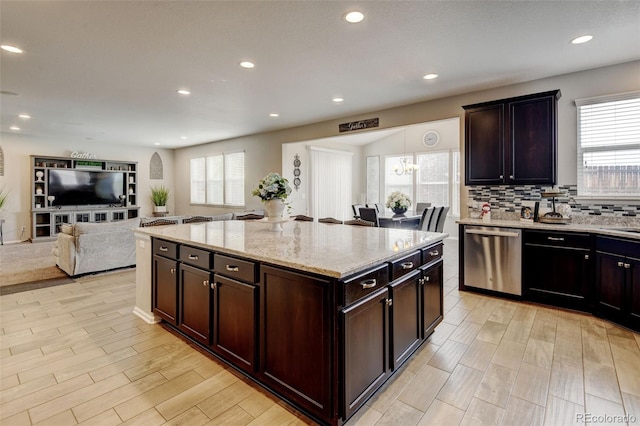 8071 Tabor St, Arvada, CO 80005 - kitchen featuring stainless steel dishwasher, healthy amount of natural light, light stone countertops, open floor plan, and recessed lighting