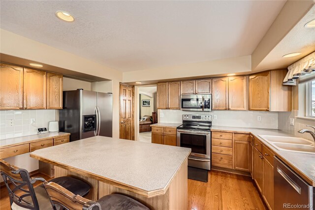 2369 Bayberry Ln, Castle Rock, CO 80104 - kitchen with stainless steel appliances, a sink, a breakfast bar area, light wood-style floors, and decorative backsplash