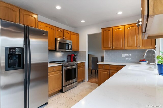 1768 E Jamison Ave, Centennial, CO 80122 - kitchen featuring appliances with stainless steel finishes, a sink, brown cabinetry, decorative backsplash, and recessed lighting