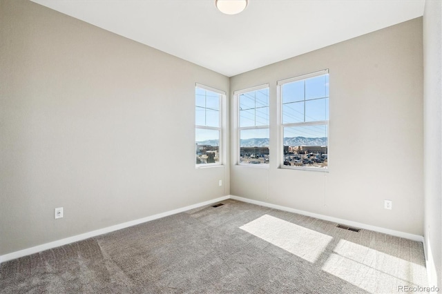 spare room featuring a mountain view and carpet floors