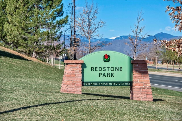 community sign featuring a mountain view and a lawn