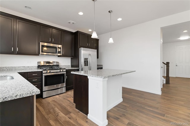 kitchen featuring a kitchen island, wood-type flooring, appliances with stainless steel finishes, and hanging light fixtures