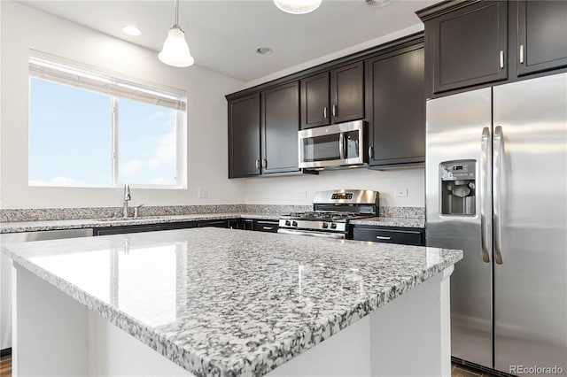 kitchen with stainless steel appliances, a kitchen island, sink, and decorative light fixtures