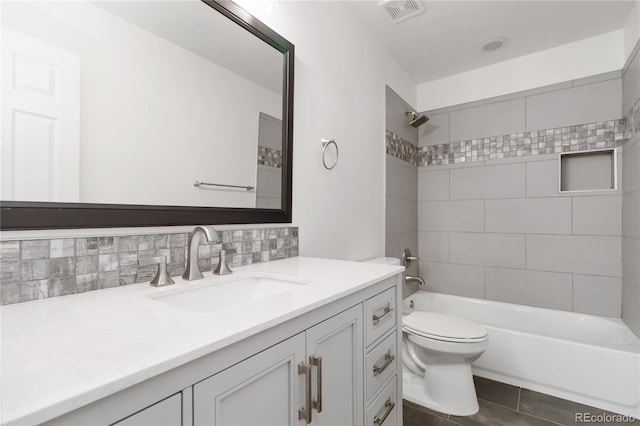 full bathroom featuring toilet, tasteful backsplash, vanity, tiled shower / bath combo, and tile patterned flooring