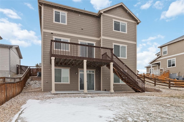 snow covered back of property featuring a wooden deck