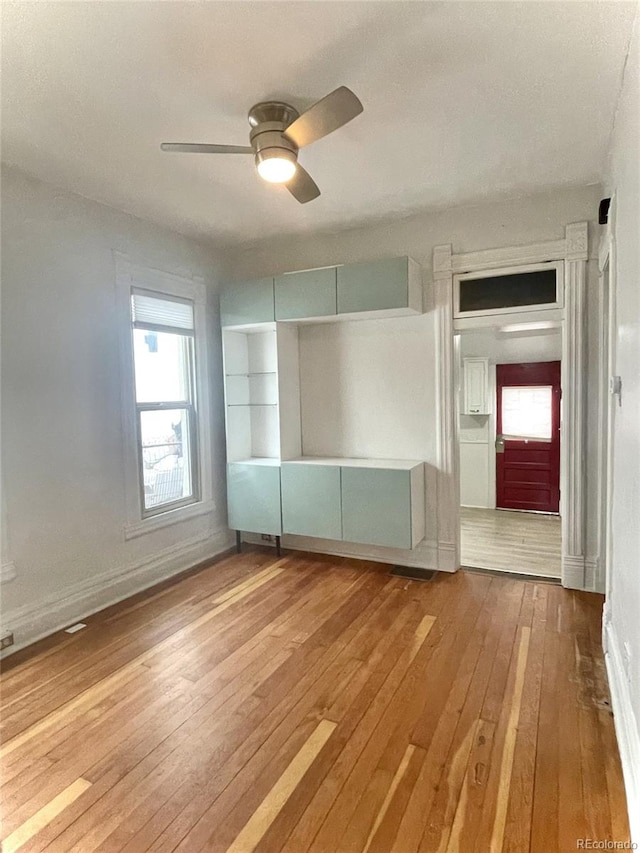 empty room featuring ceiling fan, baseboards, and hardwood / wood-style floors
