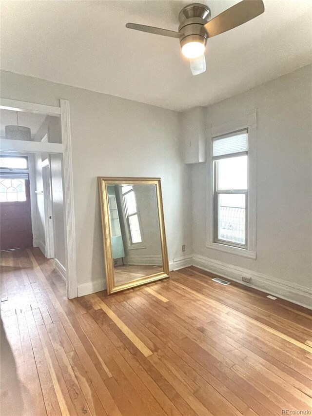 unfurnished room featuring visible vents, light wood-style flooring, baseboards, and a ceiling fan
