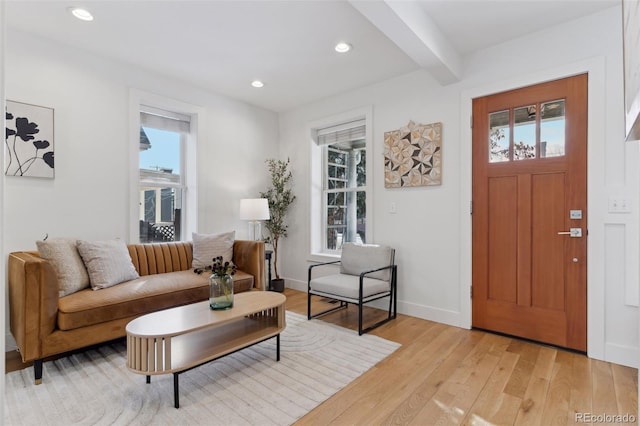 living room with beam ceiling, light hardwood / wood-style floors, and a healthy amount of sunlight