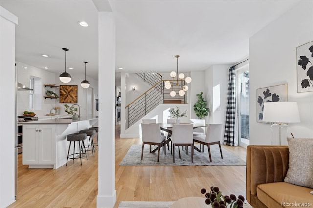 dining space with sink, an inviting chandelier, and light hardwood / wood-style floors