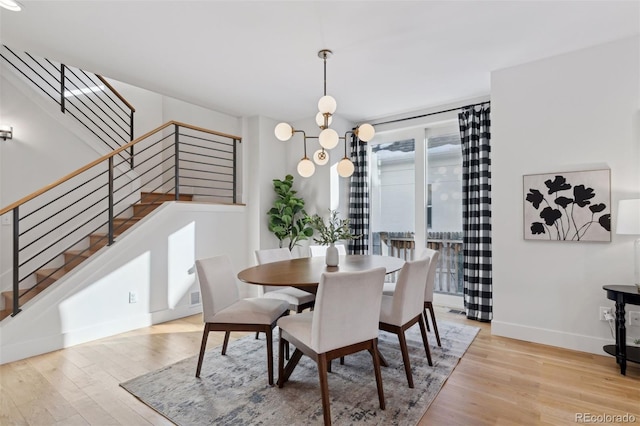 dining space with an inviting chandelier and light hardwood / wood-style flooring