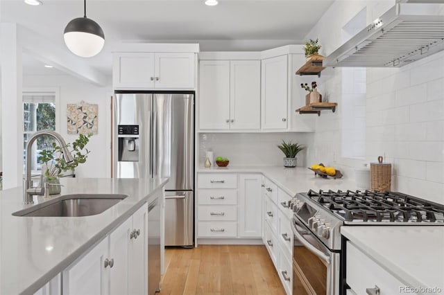 kitchen with pendant lighting, sink, white cabinetry, stainless steel appliances, and wall chimney exhaust hood