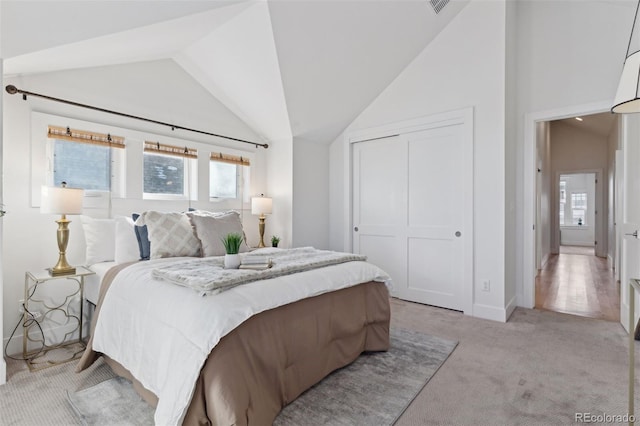 bedroom featuring multiple windows, lofted ceiling, light colored carpet, and a closet